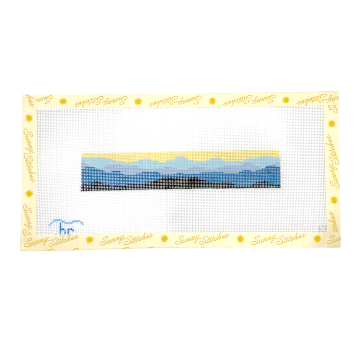 A needlepoint canvas featuring a landscape design with blue mountains, yellow sky, and dark foreground, bordered by a yellow 'Sunny Stitches' branded mat.